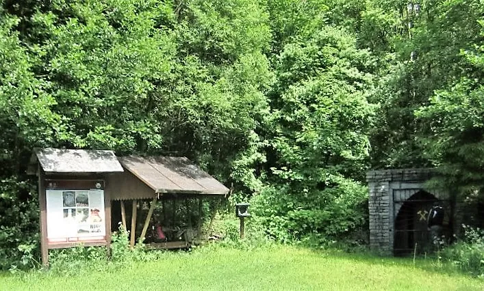 Forest hut with information board and stone portal in the countryside