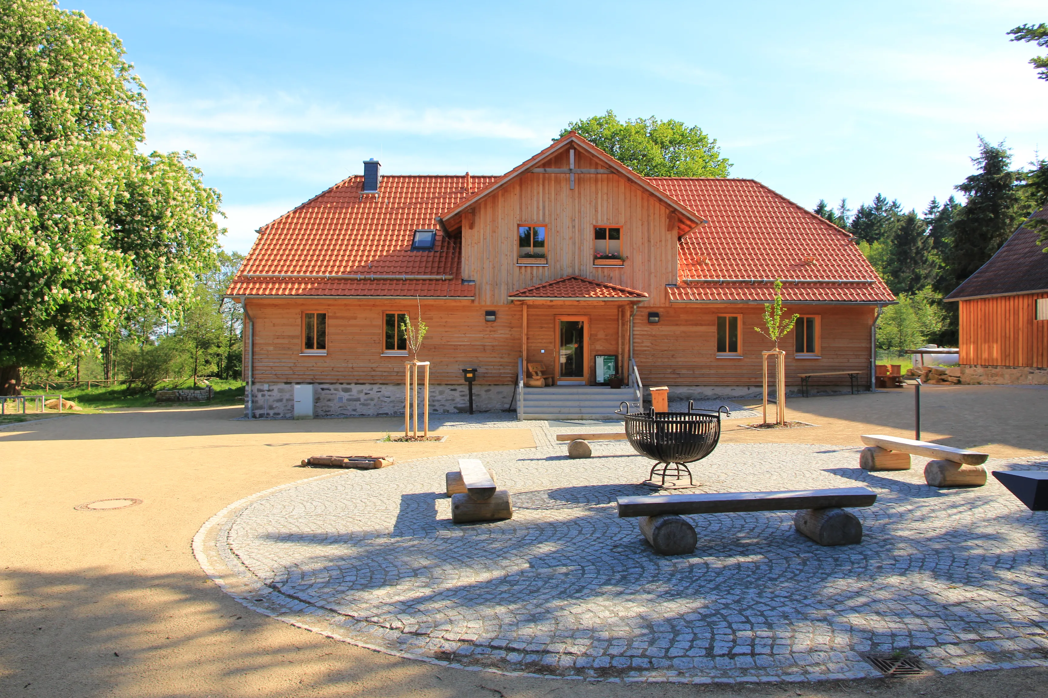 Wooden house with red roof and courtyard