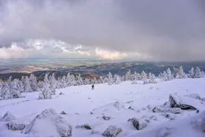 Verschneiter Brocken mit Wanderer. Winterlandschaft mit Blick ins Tal.
