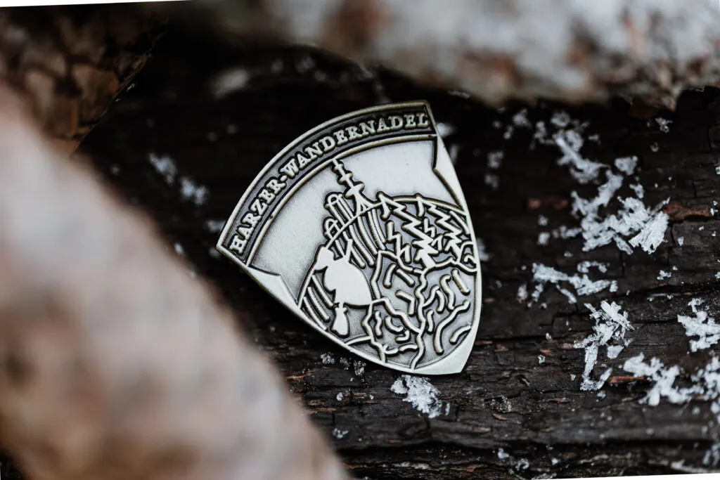 Bronze Harzer Wandernadel badge in the forest with snow